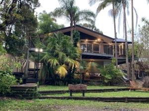 a house with a wrap around porch with palm trees at The Hideaway Jervis Bay in Vincentia