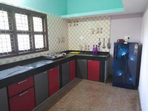 a kitchen with red and black cabinets and a refrigerator at NISARGA HOMESTAY, Dharmasthala in Dharmastala