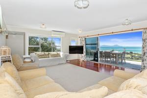 Sala de estar con sofá, TV y mesa en Surfers Lookout - Waipu Cove Holiday Home en Waipu