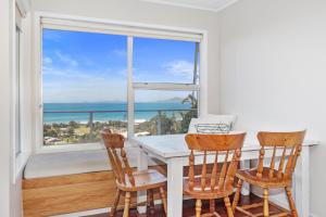 een eetkamer met een tafel en stoelen en een raam bij Surfers Lookout - Waipu Cove Holiday Home in Waipu