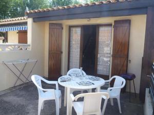 une table et des chaises blanches sur une terrasse avec une table et des chaises dans l'établissement Maison Marseillan-Plage, 3 pièces, 4 personnes - FR-1-387-127, à Marseillan