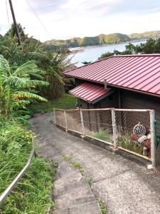 una casa con techo rojo y valla en お宿　弘法湯, en Kushimoto