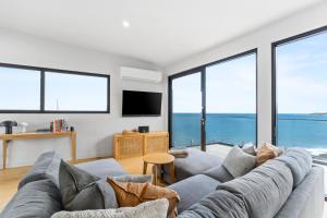 a living room with a large couch and large windows at Glassy Point - 360 degree views in Wye River