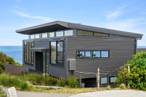 a black house with the ocean in the background at Glassy Point - 360 degree views in Wye River