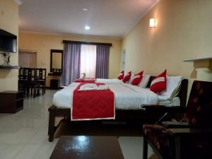 a bedroom with a large bed with red pillows at Bruton resorts in Kodaikānāl