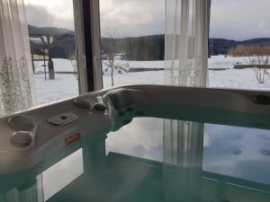 uma banheira em frente a uma janela com neve em Kuća za odmor Anima em Ravna Gora