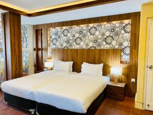 um quarto com uma cama grande e uma parede com placas em Hotel Vajra Inn & Apartments em Pokhara