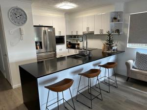 a kitchen with a counter with stools and a clock on the wall at sunrise on the beach in Gold Coast