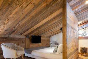 a bedroom with a wooden ceiling with a bed and two chairs at H&ocirc;tel et Spa Le Vermont in Le Grand-Bornand