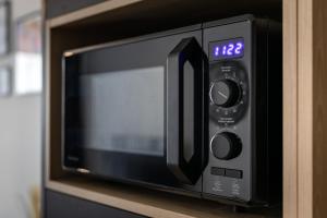 a microwave oven with a clock on a shelf at Apartament przy PILECKIEGO 33 in Biała Podlaska