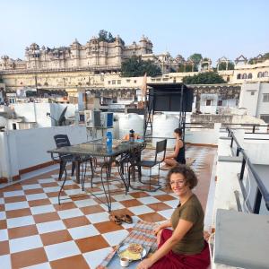 烏代浦的住宿－Nandini Paying Guest House，坐在屋顶上吃一盘食物的女人