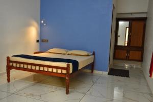 a bed in a room with a blue wall at Dhakshina Homestay in Cochin