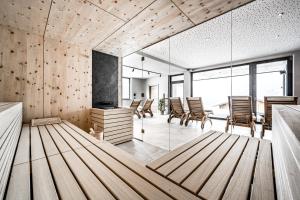een kamer met houten vloeren, stoelen en ramen bij Nativo Bergaparts in Längenfeld