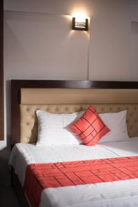 Una cama con dos almohadas rojas encima. en GOHO Rooms Badar, en Karachi