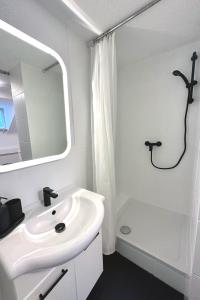 ein weißes Bad mit einem Waschbecken und einer Dusche in der Unterkunft City-Apartment in Krefeld - BEUYS Apartments - Krefeld in Krefeld