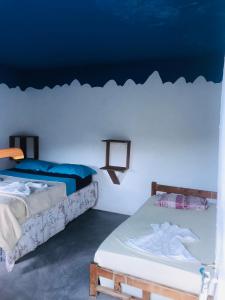 two beds in a room with a blue wall at Pensão Repouso Alegre Turismo e Aventura in Portela