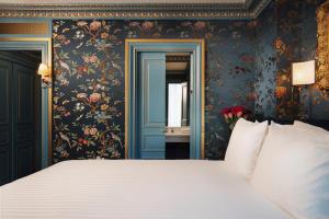 una camera da letto con un grande letto e carta da parati floreale di Maison Proust, Hotel & Spa La Mer a Parigi