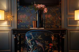 une chaise dans une pièce avec papier peint à fleurs dans l'établissement Maison Proust, Hotel & Spa La Mer, à Paris