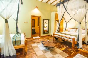 a bedroom with two beds and a table in it at Buffalo Safari Lodge in Katunguru