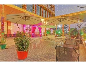 een restaurant met tafels, stoelen en parasols bij Hotel Paras Inn, Lucknow in Lucknow