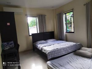 um quarto com 2 camas e 2 janelas em Bohol Sweet Home em Guindulman