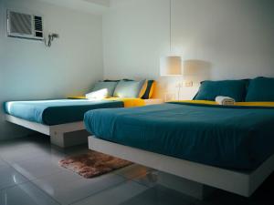 2 camas en una habitación de color azul y amarillo en Wanderlust Bed & Breakfast, en Puerto Princesa City