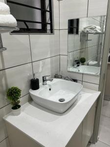 Beevap Guesthouse في بريتوريا: حمام أبيض مع حوض ومرآة