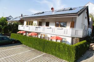 uma casa branca com guarda-chuvas vermelhos num parque de estacionamento em Gästehaus Schechter em Uhldingen-Mühlhofen