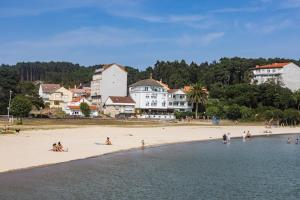un grupo de personas en una playa cerca del agua en Apartamentos Playa de Camariñas, en Camariñas