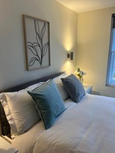 een wit bed met blauwe kussens in een slaapkamer bij Pods of Kings Cross - 6 in Londen