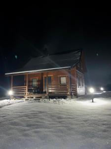 una cabaña de madera en la nieve por la noche en Domki Mazurskie Zacisze Jeziora Sunowo en Ełk
