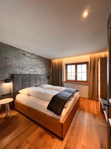 a bedroom with a large bed and a stone wall at Schulhaus Tirol in Zell am Ziller