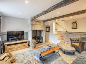 a living room with a fireplace and a tv at Hob Cote in Heptonstall