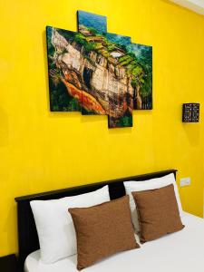 a bed with four paintings on a yellow wall at Funwhales Rest House in Negombo