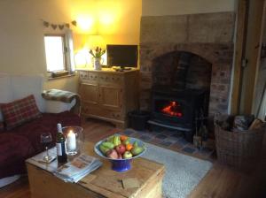 a living room with a fireplace and a bowl of fruit at Beautiful Stone Riverside Cottage in Waterfall