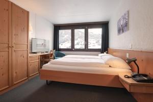 a bedroom with a bed and a desk with a computer at Jungfrau Lodge, Annex Crystal in Grindelwald