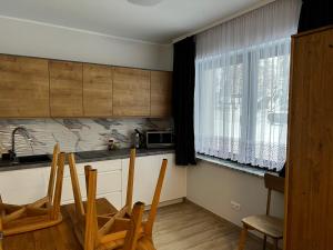 a kitchen with a table and chairs and a window at Apartament Miś in Zakopane