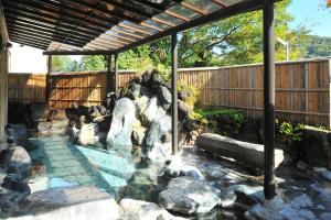 a swimming pool with a waterfall in a garden at Shuzenji Onsen Hotel Takitei in Izu