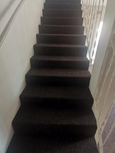 a staircase with black treads and a black carpet at Luca's Place in Durban