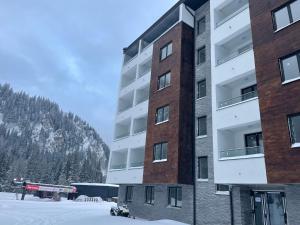 a tall building with snow in front of it at Apartman Magi Jahorina in Jahorina
