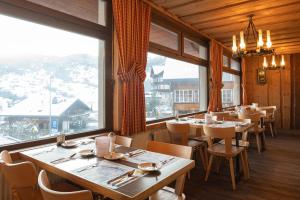 a restaurant with tables and chairs and a large window at Basic Rooms Jungfrau Lodge in Grindelwald