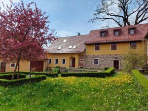 a large yellow house with a yard with flowers at Martinkovice 201 Broumov in Martínkovice