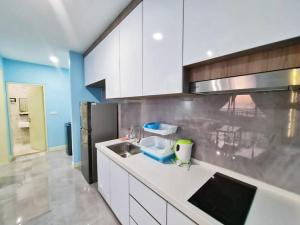 uma cozinha com armários brancos, um lavatório e um frigorífico em FullySeaView#2Bedrooms#Netflix#FreeParking#PrivateBathtub#RoomWithBalcony#ImperioResidence em Malaca