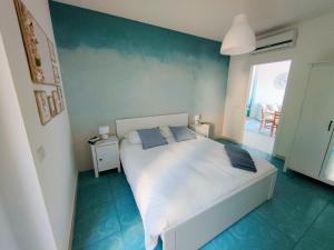 1 dormitorio con 1 cama blanca grande con almohadas azules en Le Sfumature del Mare, en San Vito Chietino