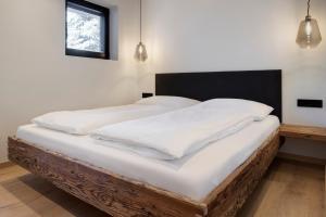 a bed with white sheets and pillows on it at LUXE VISTA Mountain Chalet Cermis - direkt an der Skipiste und Alm in Cavalese