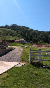 a wooden fence in a field with a house at Casa - Sítio da Tabi - Lagoinha-SP in Lagoinha