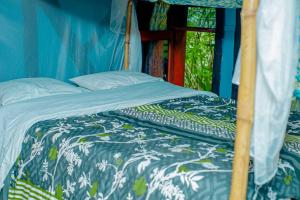 a bed in a room with a blue and white comforter at Fravan Eco Resort By Apogee in Ruhengeri
