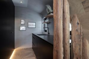 a kitchen with a sink and a wooden log wall at LUXE VISTA Mountain Chalet Cermis - direkt an der Skipiste und Alm in Cavalese