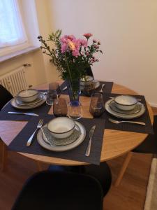 una mesa con platos y un jarrón de flores. en Palazzo Penco Apartment, en Génova