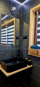 La salle de bains est pourvue d'un lavabo noir et d'un miroir. dans l'établissement Trzy Szczyty-Wysoka, à Grywałd